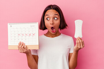 Young woman holds calendar, worried about approaching menstrual cycle.