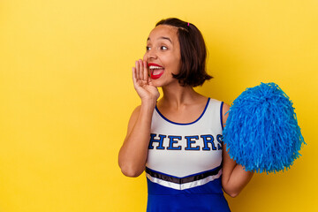 Young cheerleader mixed race woman isolated on yellow background shouting and holding palm near opened mouth.