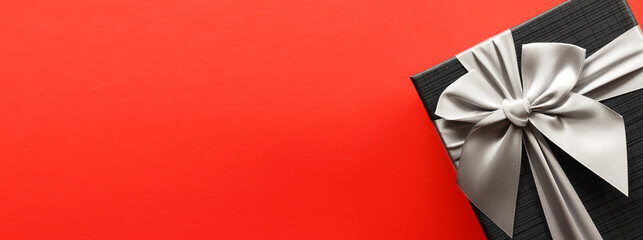 Black gift box on red background with copy space.