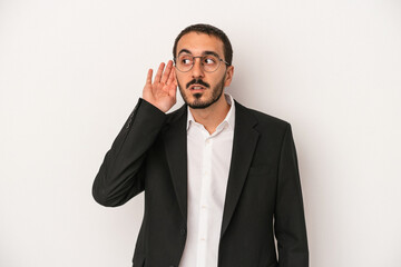 Young caucasian business man isolated on white background trying to listening a gossip.