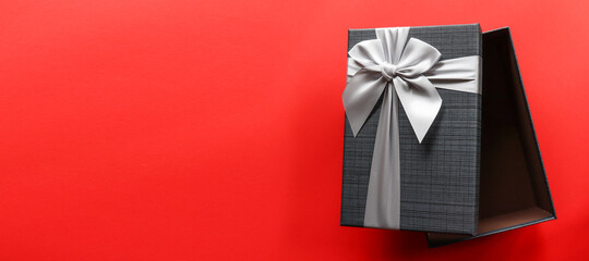 Black gift box on red background with copy space.