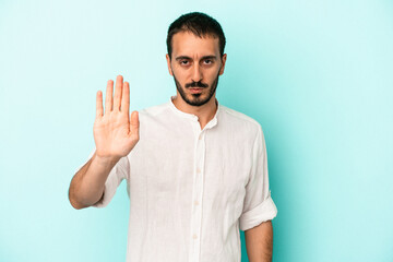 Naklejka premium Young caucasian man isolated on blue background standing with outstretched hand showing stop sign, preventing you.