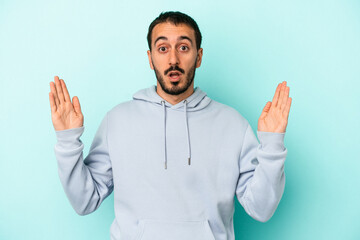 Young caucasian man isolated on blue background holding something little with forefingers, smiling and confident.