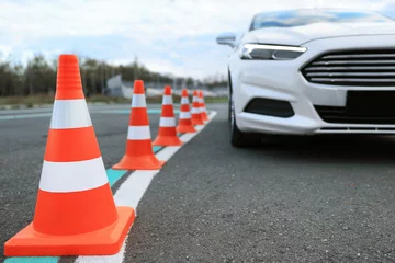Selbstklebende Fototapeten Modern car on test track with traffic cones, closeup. Driving school © New Africa