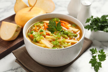 Bowl of delicious turnip soup on white marble table