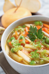 Bowl of delicious turnip soup on white marble table, closeup