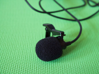 Lavalier microphone on a green background, close-up. A lavalier microphone or lavalier is a small...