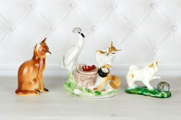 Collection of three porcelain figurines - a fox sitting, a fox and a crane having lunch, a dog...