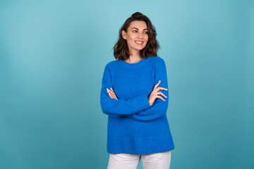 Woman in a blue knitted sweater and natural make-up, curly short hair, with an infectious radiant...