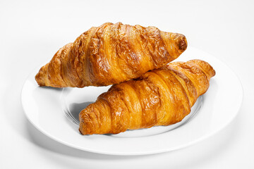 Two French croissants on white plate on white background.