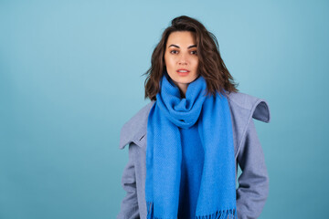 Spring autumn portrait of a woman in a blue knitted sweater, scarf and gray coat, posing...