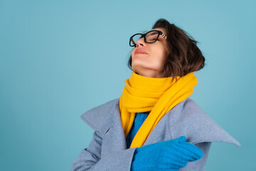 Spring autumn portrait of a woman in a blue knitted sweater, glasses, a yellow bright scarf and a...