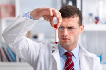 Viorolog researcher examining a sample from test tube working in a modern equipped laboratory.