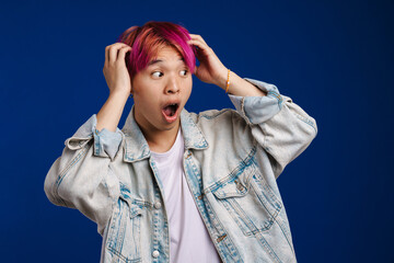 Asian boy expressing surprise while holding his head