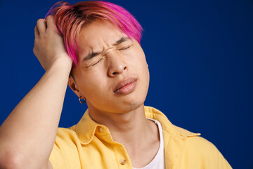 Asian boy with headache frowning while holding his head