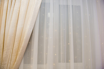 Curtain with tulle on the window. The interior of the room with draped curtains.