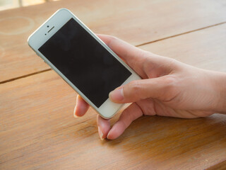 hand holding a cell phone on a wooden table