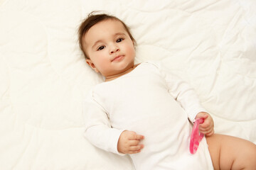 Little cute baby girl on the blanket with a heart shaped toy