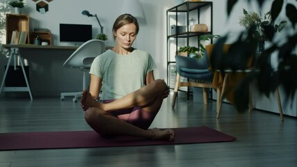 Slow motion portrait of attractive young lady meditating alone in modern apartment enjoying peace and quiet. People and healthy lifestyle concept.