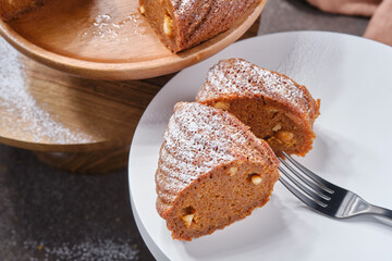 Sliced Muffin cake or Bundt cake decorated icing sugar on the plate and stand with fork. Shallow depth of field
