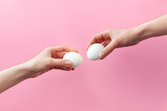 Woman hands holding Easter eggs for knocking on pink background. Easter celebration or creative concept. Adam creation
