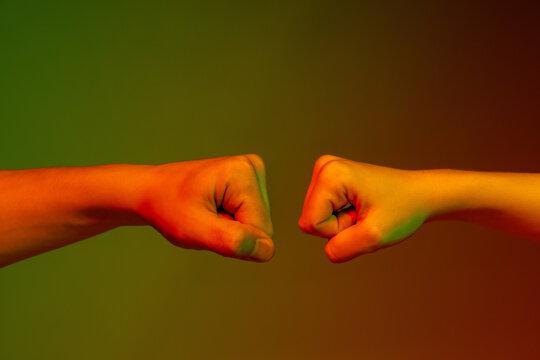Authentic male and female hands clenched into fists gesturing on dark studio background