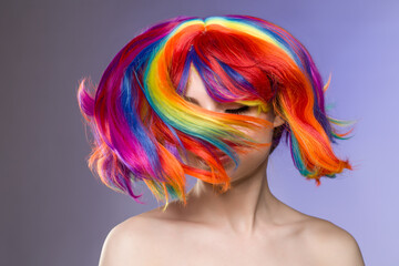 Woman hair as color splash. Rainbow up do short haircut. Beautiful young girl model with glowing  healthy skin. Smiling, positive and happy woman