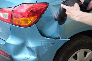 Insurance worker taking photo on camera of dented fender on street side for emergency service after car accident. Road safety and insurance concept