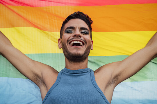 Happy homosexual man celebrating gay pride holding rainbow flag symbol of LGBTQ community