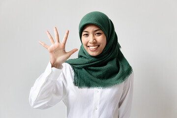 Young Muslim woman pointing up five fingers for raising 5 points concept