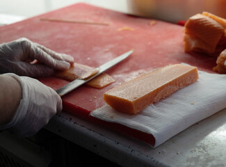Photo of male hands in gloves which cuts a red fish on a board. Seafood and food