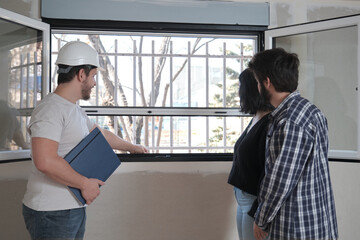 Fototapeta premium Architect shows the insect screen of the window of a new apartment to a couple.