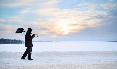 Mature man is carrying a shovel for snow cleaning © antonivano