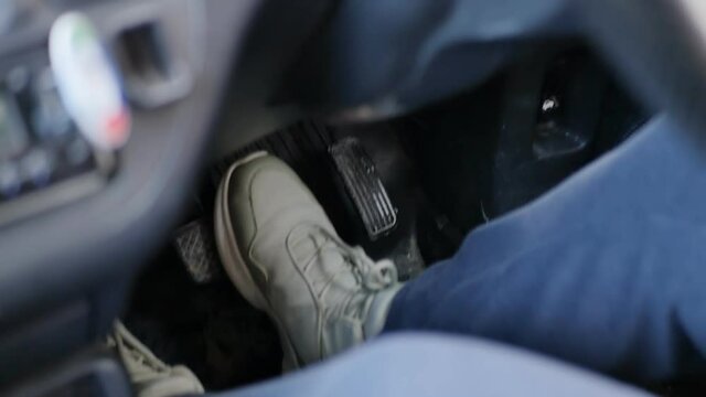legs of a female driver in sneakers press the pedals in the car