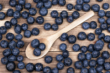 Blueberry background. Ripe blueberry with wooden spoon on wooden background.