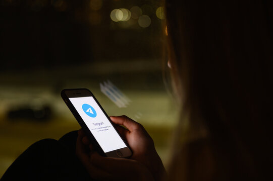 Vladimir, Russia - January 2022: Telegram application on a smartphone in the hands of a girl at night. Selective focus on the logo, narrow focus.