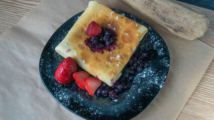 Classic american pancake with berry on black plate background. Crepe with blueberry and strawberry.