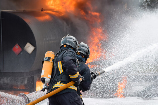 Dos bomberos enfrentándose a un fuego y apagándolo con una manguera