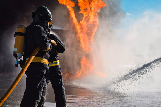 Una pareja de bomberos frente a un muro de llamas
