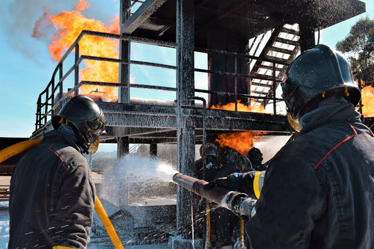 Dos bomberos apagando un peligroso fuego en una fábrica