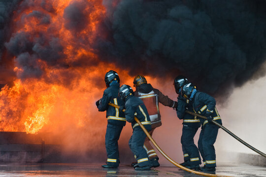 Grupo de bomberos apagando un fuego rodeados de humo