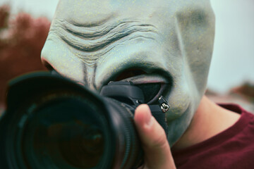 Persona disfrazada con una máscara de alienígena sacando fotos con una cámara