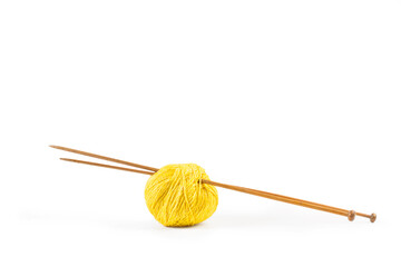 Un ovillo de lana amarilla con dos agujas de madera para tejer sobre un fondo blanco liso y aislado. Vista de frente y de cerca. Copy space - obrazy, fototapety, plakaty