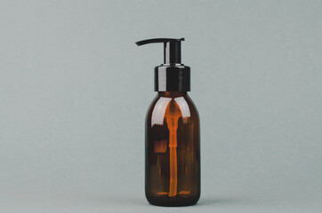 Cosmetic bottle with a dispenser on a gray background with space for text.