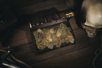 Treasure chest with a gold coins,dagger and human skull on a pirate captain table in the light of...