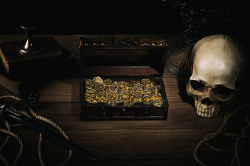 Treasure chest with a gold coins,dagger and human skull on a pirate captain table in the light of...