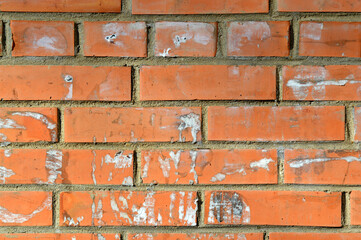 Fototapeta premium Old orange brick wall. Painted distressed wall surface. Vintage red brick wall with signs of old ads on it. Urban photo background for design. Building Facade With Damaged Plaster. 