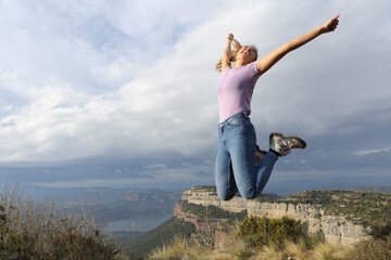 Excited woman jumping celebrating in nature