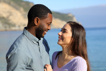 Interracial couple in love looking each other on the beach