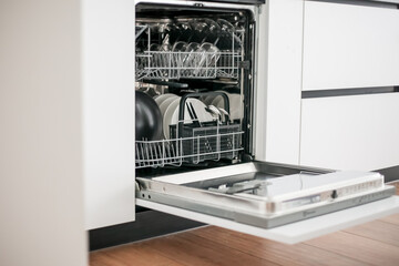 Open dishwasher in the white kitchen.
